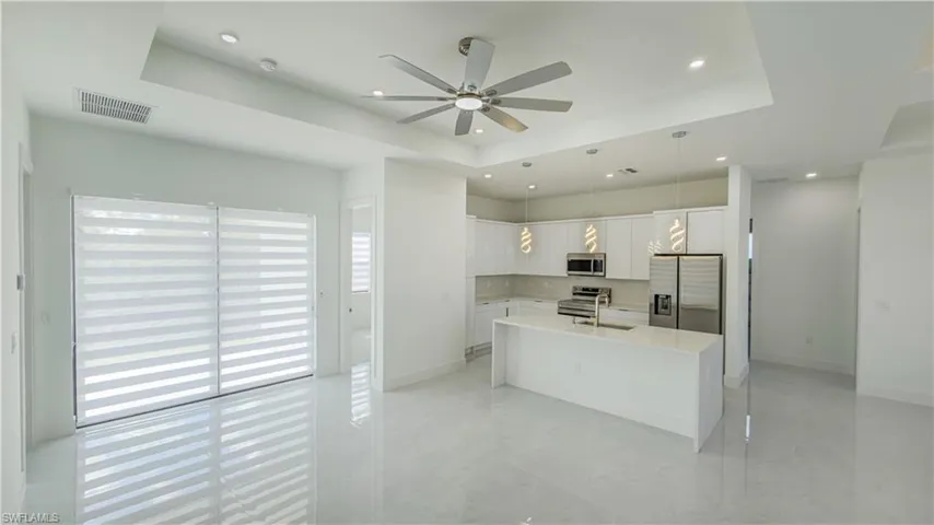 Kitchen featuring a raised ceiling, white cabinets, appliances with stainless steel finishes, and recessed lighting