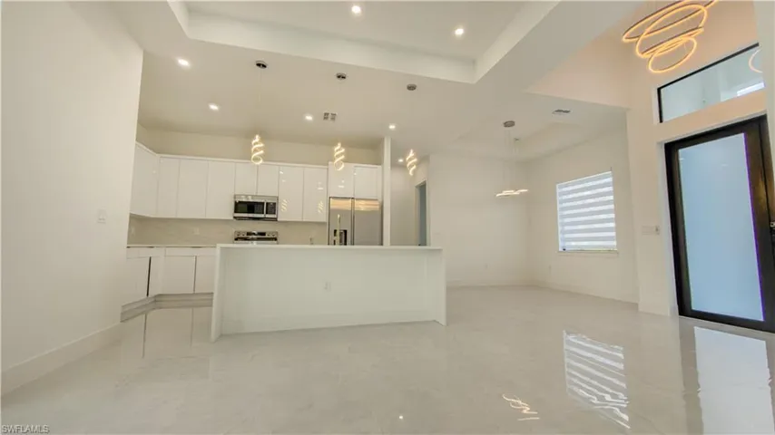 Kitchen featuring white cabinets, a center island, decorative light fixtures, appliances with stainless steel finishes, and modern cabinets