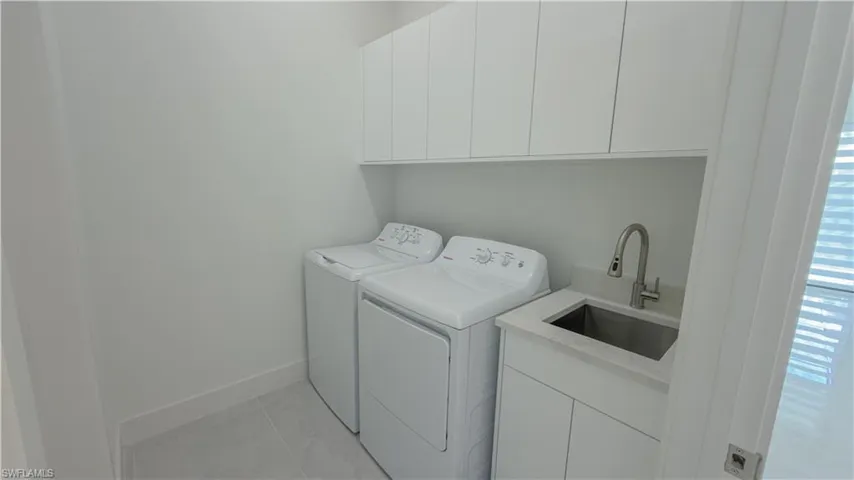 Laundry area featuring washing machine and clothes dryer, cabinet space, and light tile patterned flooring