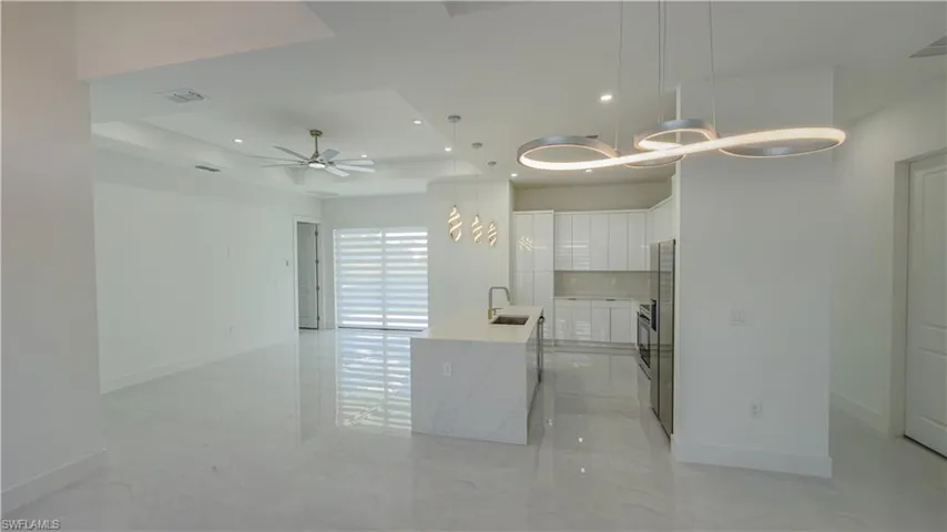 Kitchen featuring white cabinets, recessed lighting, light stone counters, hanging light fixtures, and a tray ceiling