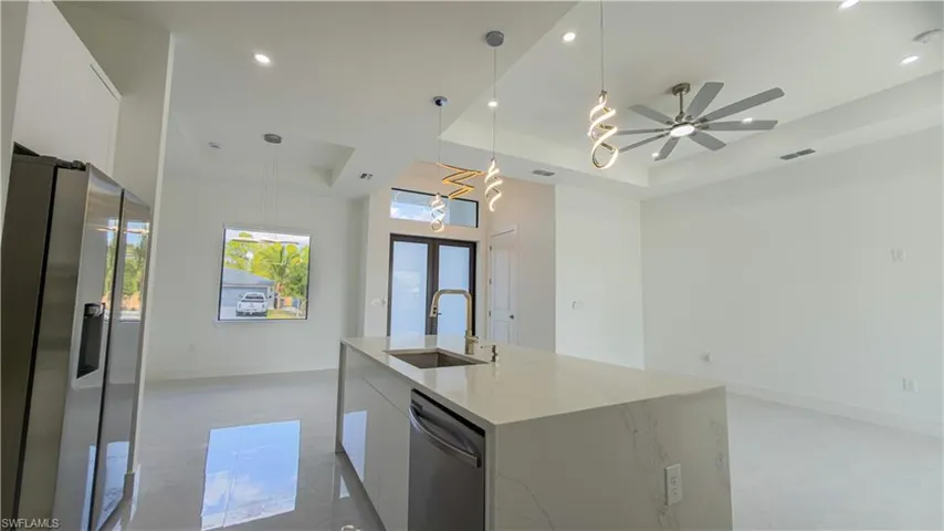 Kitchen with white cabinets, a raised ceiling, stainless steel appliances, decorative light fixtures, and recessed lighting