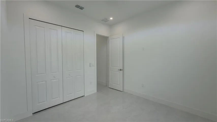 Unfurnished bedroom with a closet, light marble finish floors, and recessed lighting