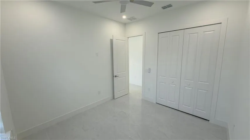 Unfurnished bedroom featuring a closet, a ceiling fan, and light marble finish flooring