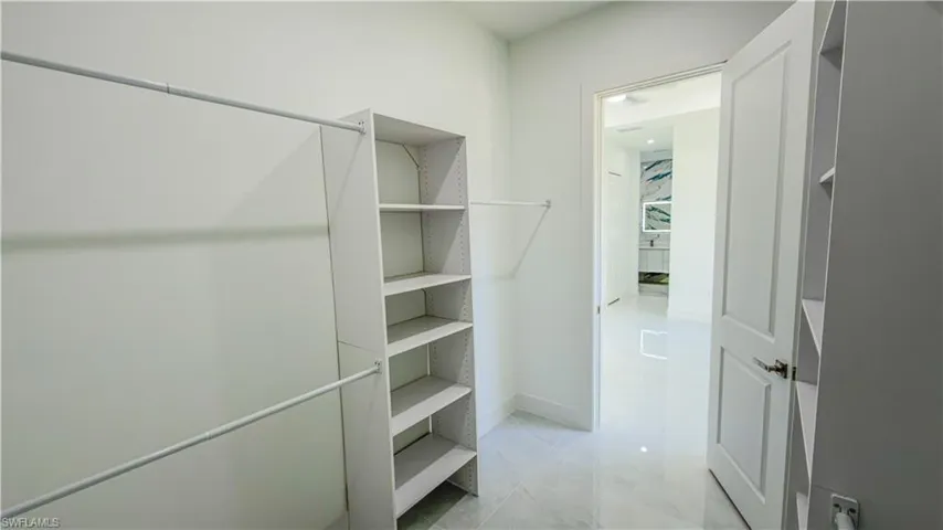 Walk in closet with light marble finish floors