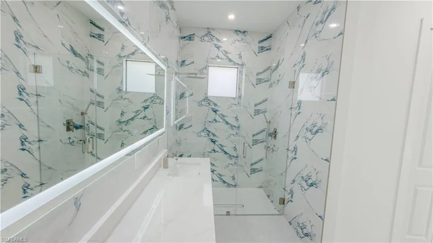 Bathroom featuring vanity and a marble finish shower