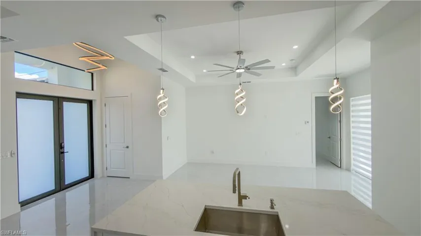 Kitchen with light stone counters, a tray ceiling, pendant lighting, ceiling fan, and recessed lighting