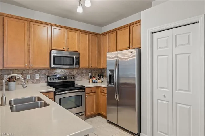 Kitchen featuring stainless steel appliances, sink, tasteful backsplash, and light tile patterned floors