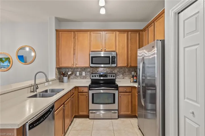 Kitchen featuring tasteful backsplash, sink, light tile patterned floors, and stainless steel appliances