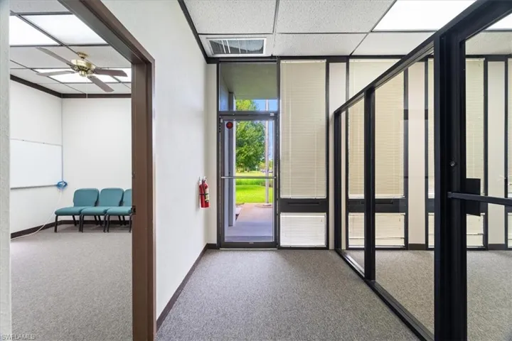 Carpeted foyer featuring a wall of windows, ceiling fan, and a drop ceiling