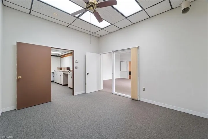 Unfurnished bedroom with carpet flooring, a drop ceiling, and ceiling fan
