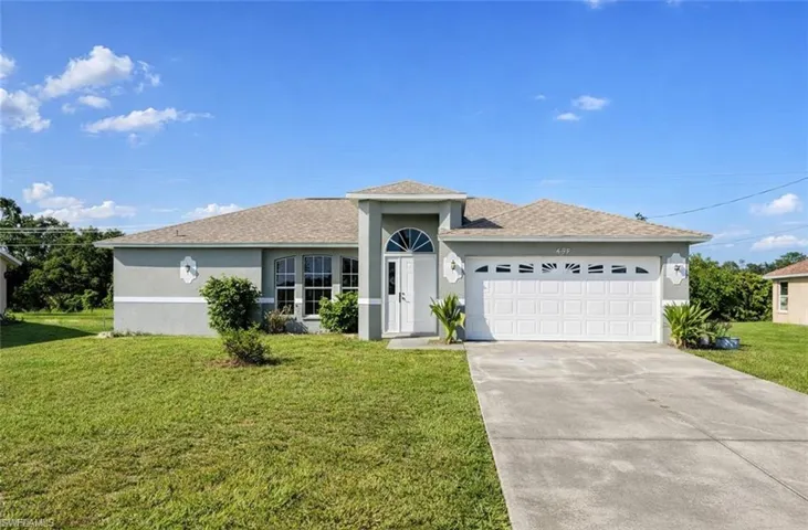 Single story home featuring stucco siding, a front yard, a shingled roof, an attached garage, and concrete driveway
