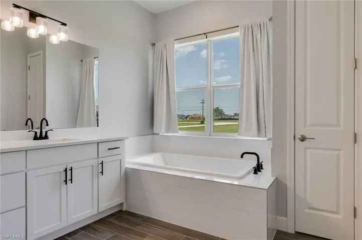 White soaking tub with matte black fixtures