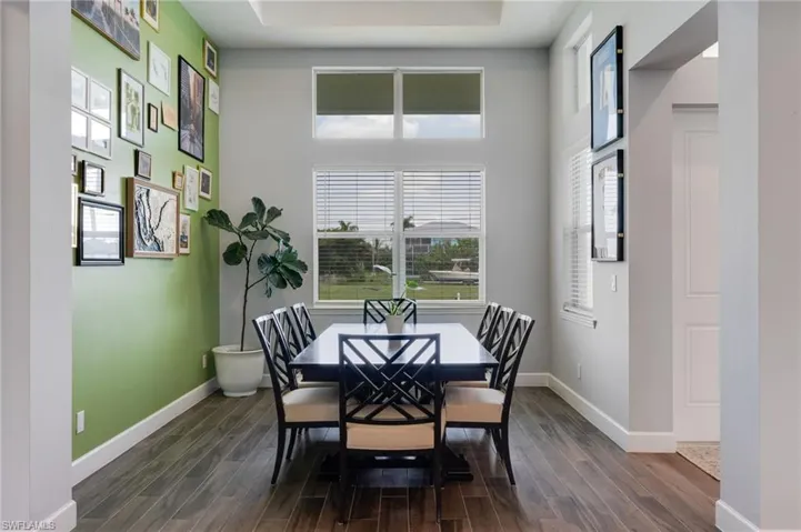 Dining area featuring wood-finish flooring, high ceilings with a tray detail, and expansive windows offering outdoor views
