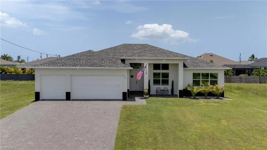 Contemporary single-story residence featuring a three-car garage, paver driveway, and a shingled roof
