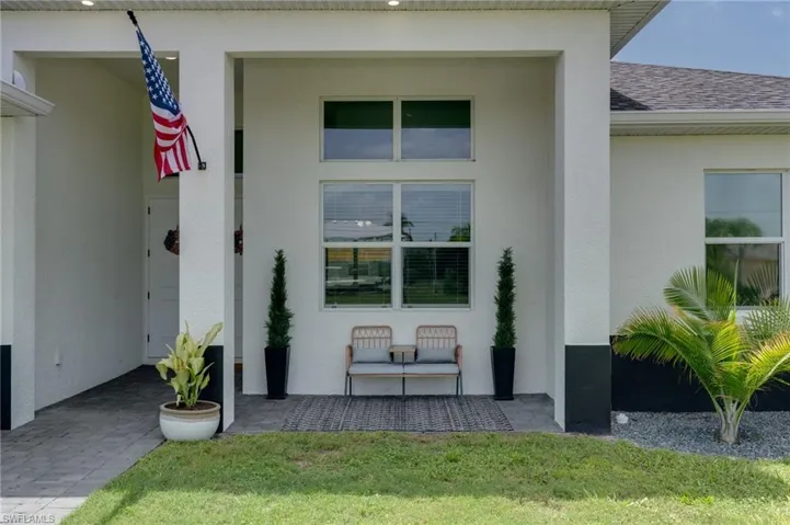 Contemporary exterior featuring a covered entry, stucco finish, and a paved walkway