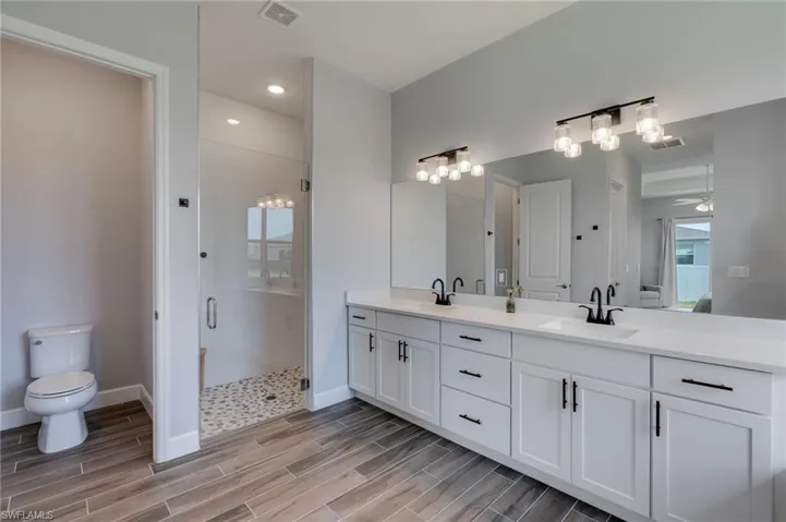 Dual vanity with white cabinetry, matte black hardware, and an expansive mirror