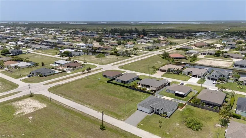 Aerial perspective showcasing a residential neighborhood with a mix of established homes and undeveloped land parcels