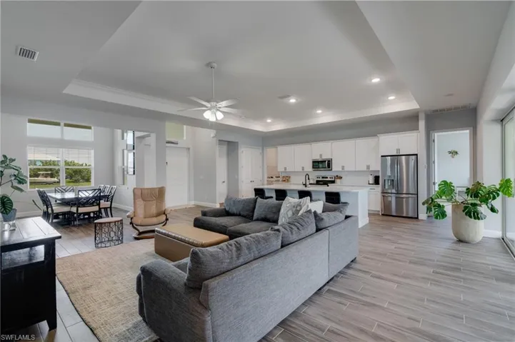 Spacious living area featuring wood-look tile flooring, recessed lighting, and a tray ceiling