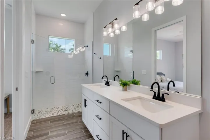 Modern bathroom featuring a dual vanity with white cabinetry, matte black hardware, and an off white countertop