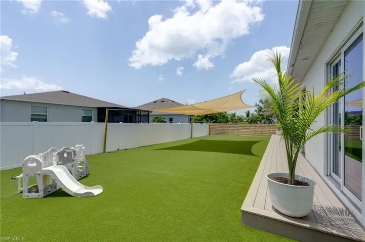 Expansive backyard featuring synthetic turf, a privacy fence, and a sun sail shade structure