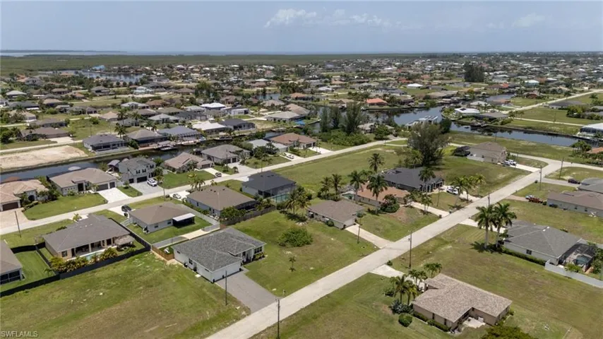 Aerial perspective showcasing a residential community with numerous single-story homes, many featuring private boat docks on canals