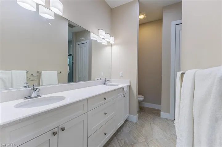 Full bath featuring double vanity and commode.