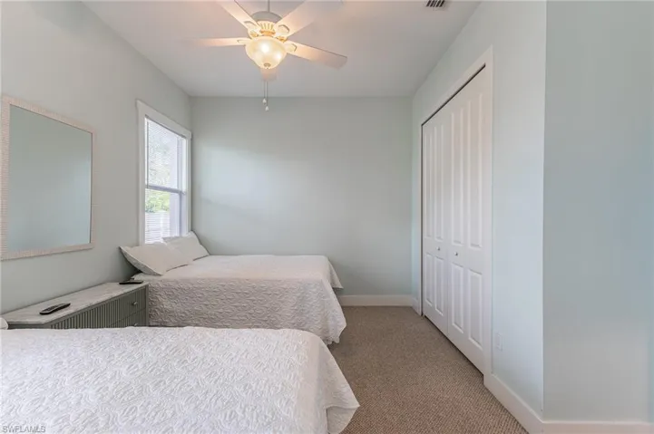 Bedroom with light colored carpet, a closet, and ceiling fan