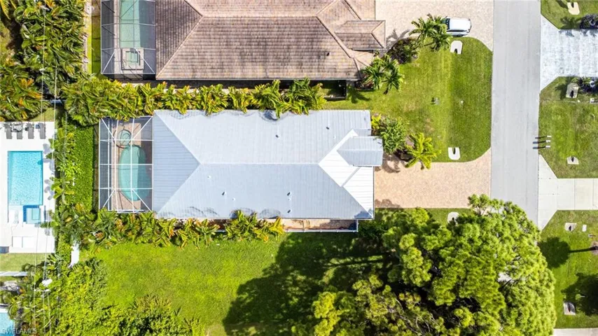 Bird's eye view of a pool area, newer metal roof, and tropical landscaping.