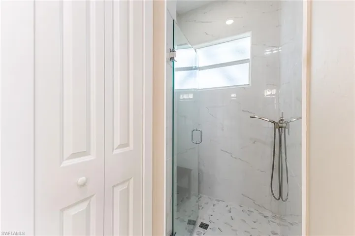 Full bathroom featuring a marble finish shower and a closet