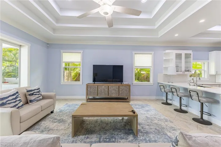 Living area with a tray ceiling, recessed lighting, and ceiling fan