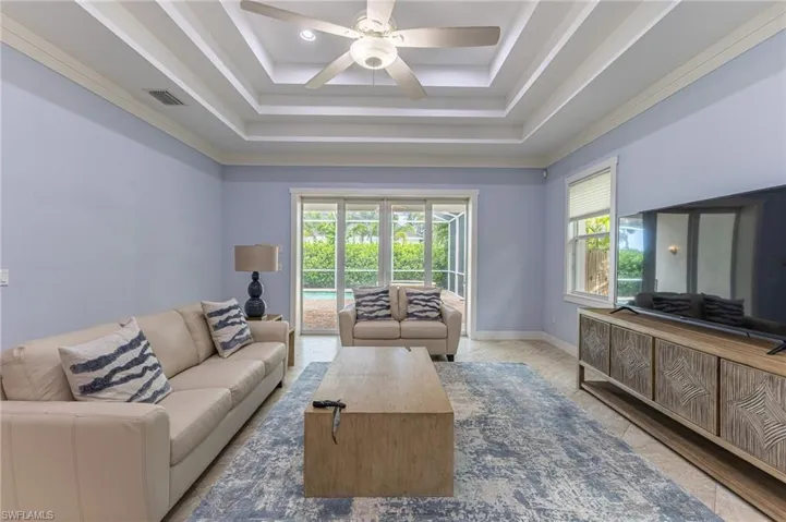 Living area with a tray ceiling, tile patterned flooring, and ceiling fan