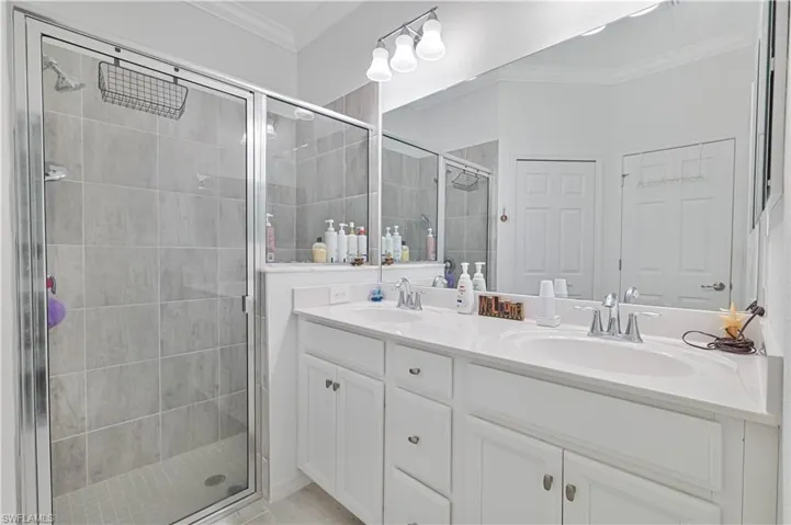Full bathroom with crown molding, double vanity, and a shower stall