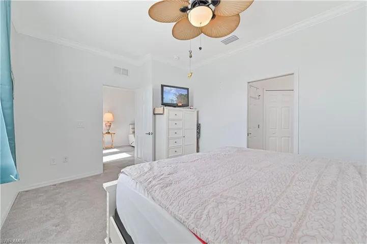 Bedroom featuring crown molding, light colored carpet, and a ceiling fan