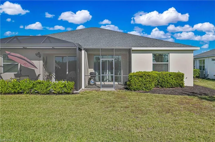 Back of property with roof with shingles, a yard, glass enclosure, a sunroom, and stucco siding