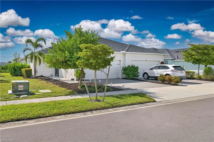View of property hidden behind natural elements featuring decorative driveway, a garage, and a front yard