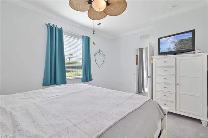 Carpeted bedroom with crown molding and ceiling fan