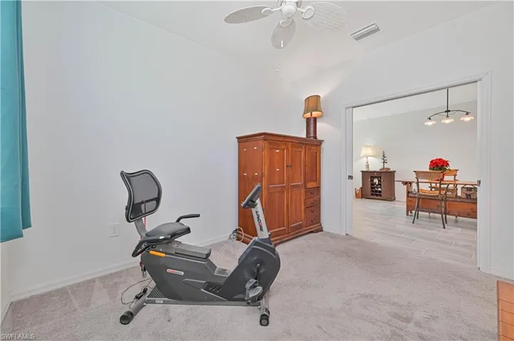 Workout room with light carpet, a ceiling fan, and a chandelier