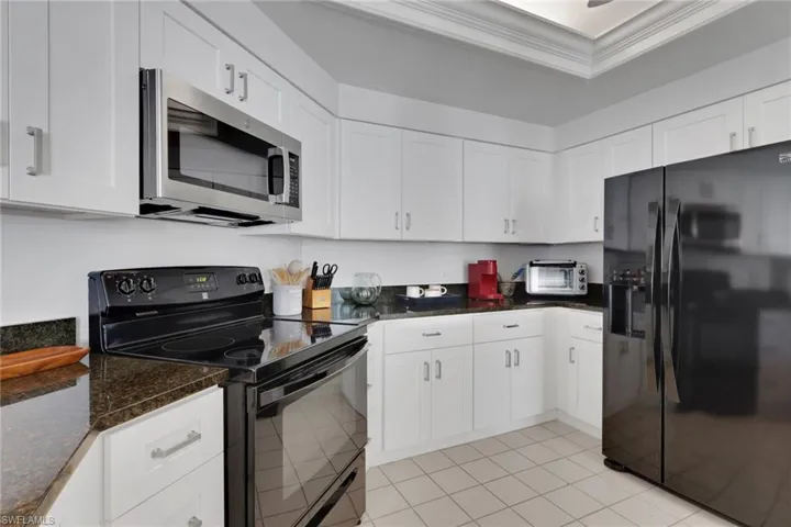 Kitchen featuring black appliances, white cabinetry, and crown molding