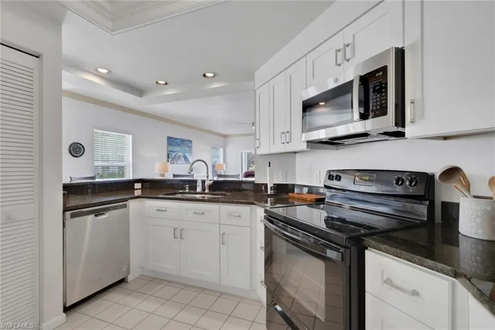 Kitchen featuring stainless steel appliances, white cabinetry, crown molding, plenty of natural light, and a raised ceiling