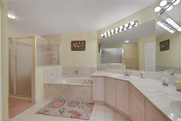 Full bath with a bath, double vanity, a shower stall, and light tile patterned flooring