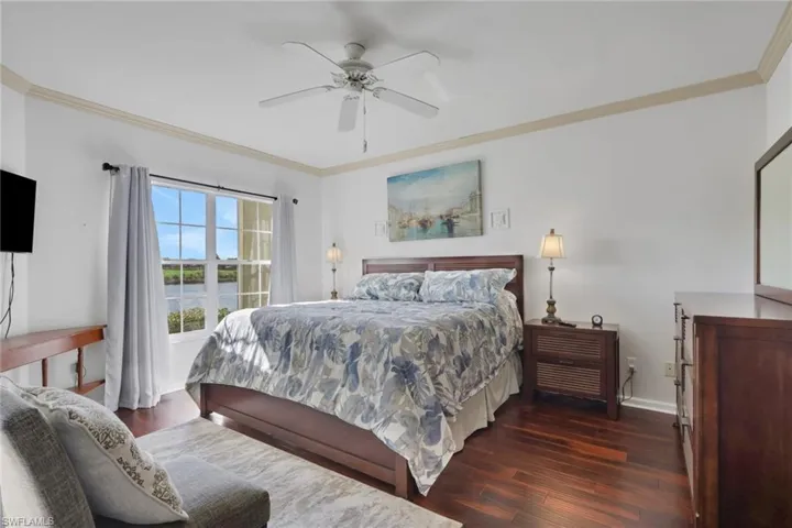 Bedroom featuring ornamental molding, dark wood-style floors, and a ceiling fan