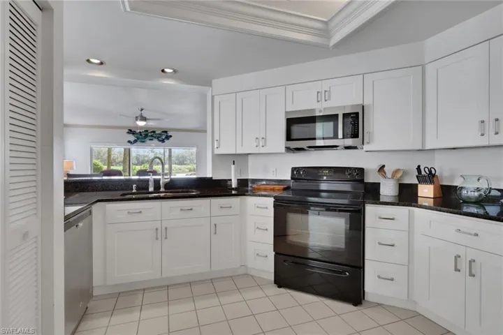 Kitchen with stainless steel appliances, ornamental molding, dark stone countertops, white cabinets, and recessed lighting