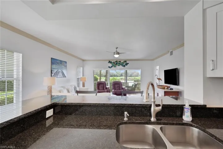 Kitchen featuring open floor plan, dark stone countertops, ceiling fan, and ornamental molding