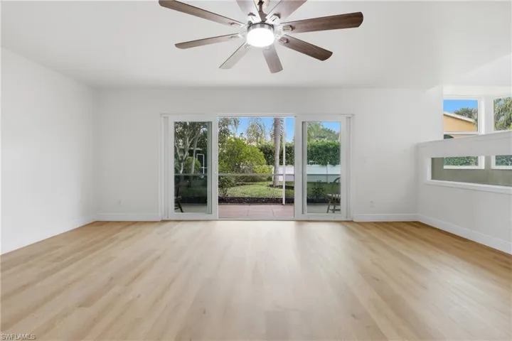 Empty room with light wood finished floors, a ceiling fan, and healthy amount of natural light