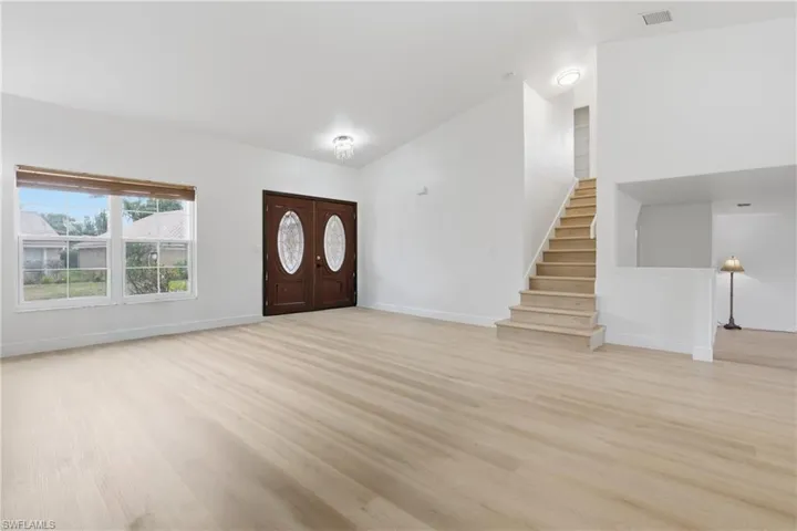 Entrance foyer with light wood-style floors and lofted ceiling