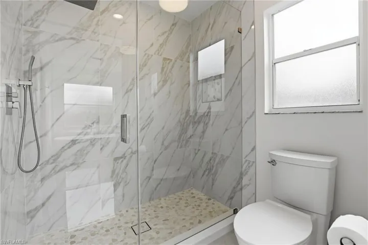Full bathroom with toilet and a marble finish shower