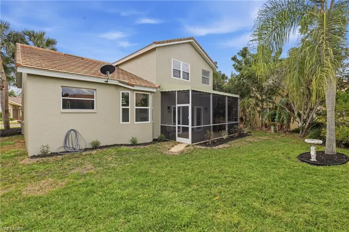 Rear view of property featuring stucco siding, a yard, a sunroom, and a tile roof