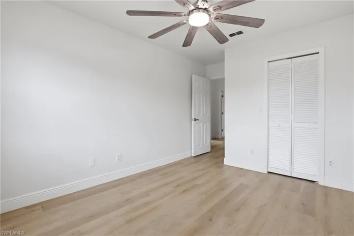 Unfurnished bedroom with light wood-style flooring, ceiling fan, and a closet
