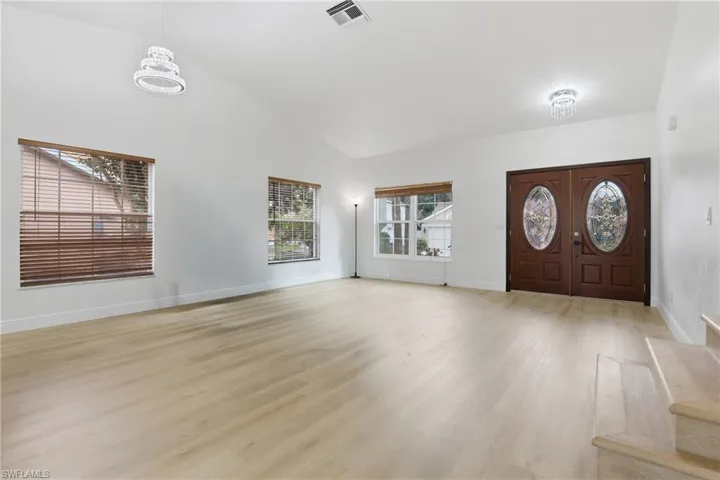 Foyer entrance with lofted ceiling and light wood-type flooring