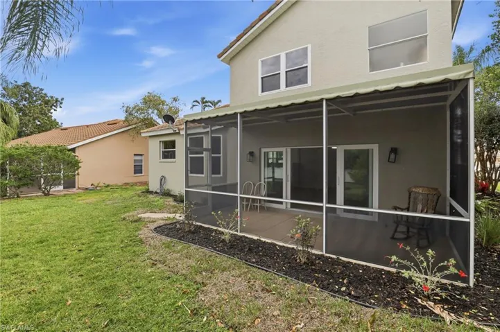 Rear view of house with stucco siding, a sunroom, and a yard
